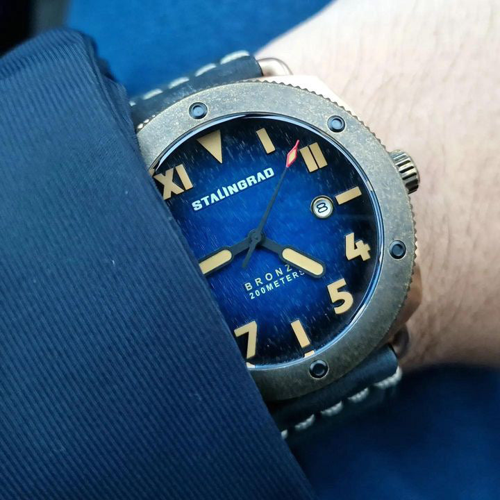 Mens Bronze watch blue dial and california dial, on a mans wrist wearing a blue jacket