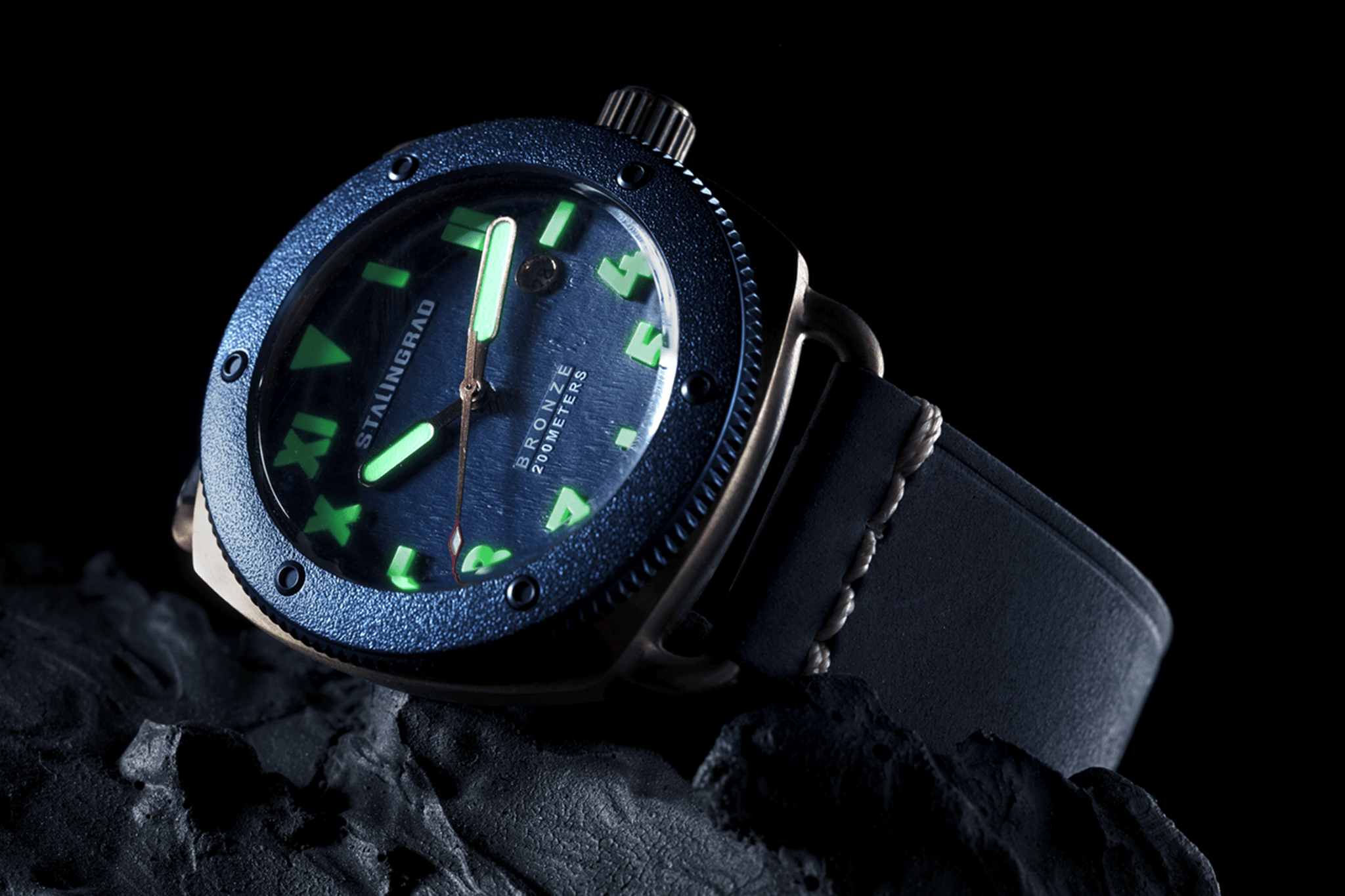 Stalingrad Bronze Men's watch with blue dial on a rock showing hands glowing with lume