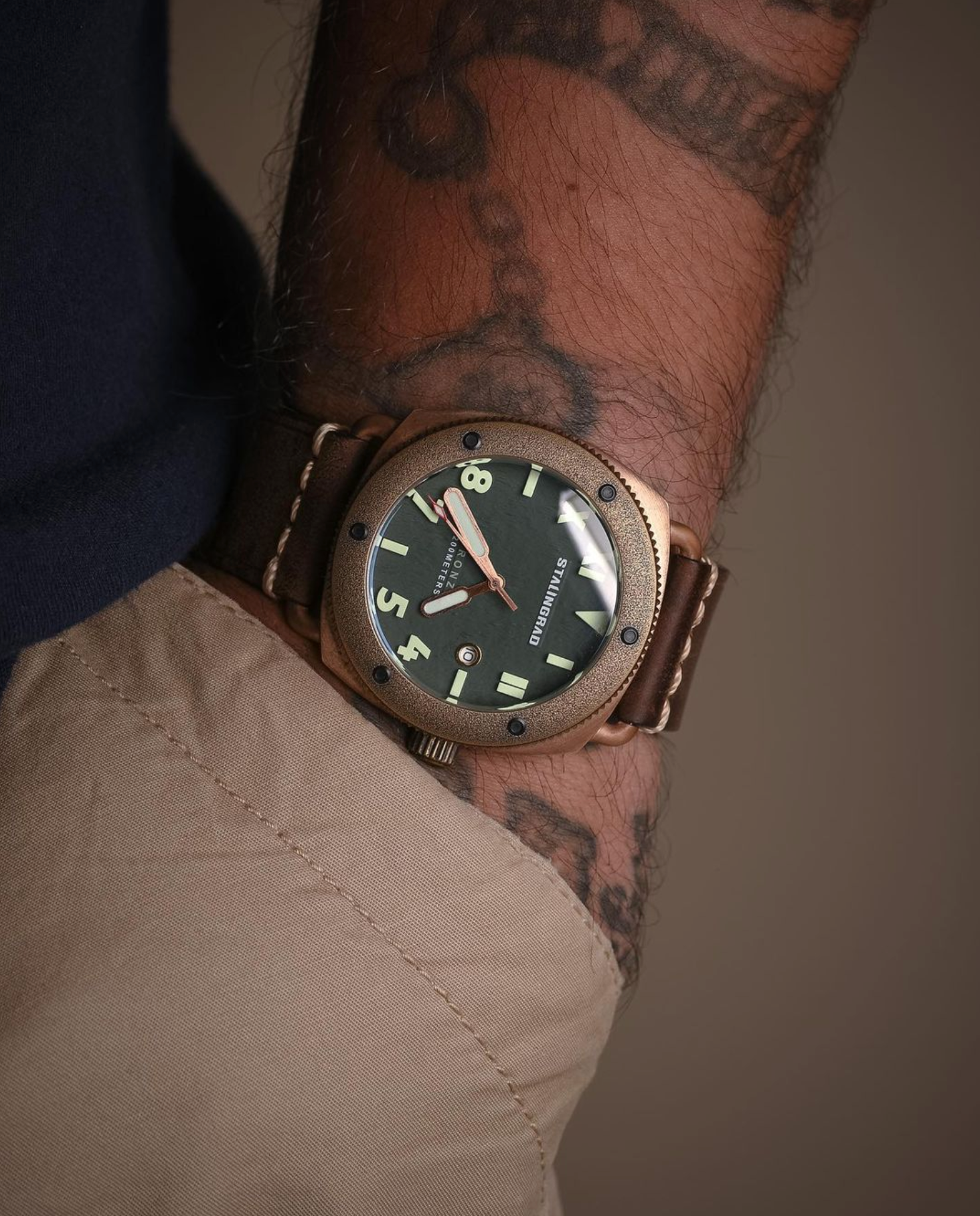 Stalingrad Bronze Watch Defender 200m WR Green dial on a man with tattoos, khaki pants and blue shirt