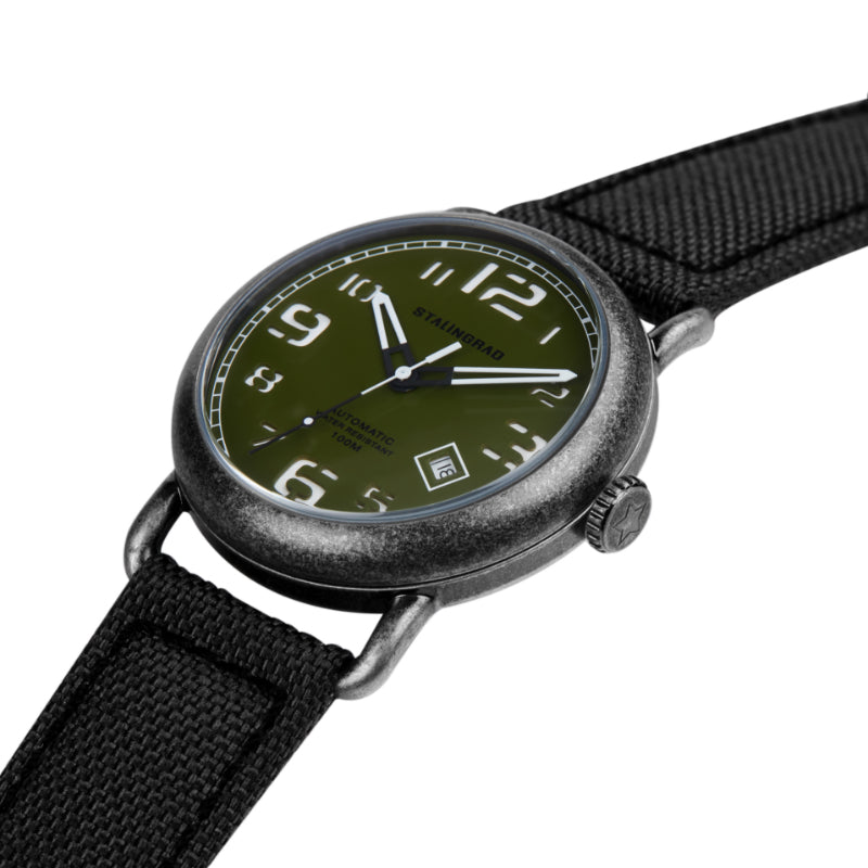 Stalingrad Rodim Watch with a sandwich dial. Green Dial with White hands and numbers dial, Silver case and a black cordura strap with a green nato strap next to it diagonal view of watch on white background.