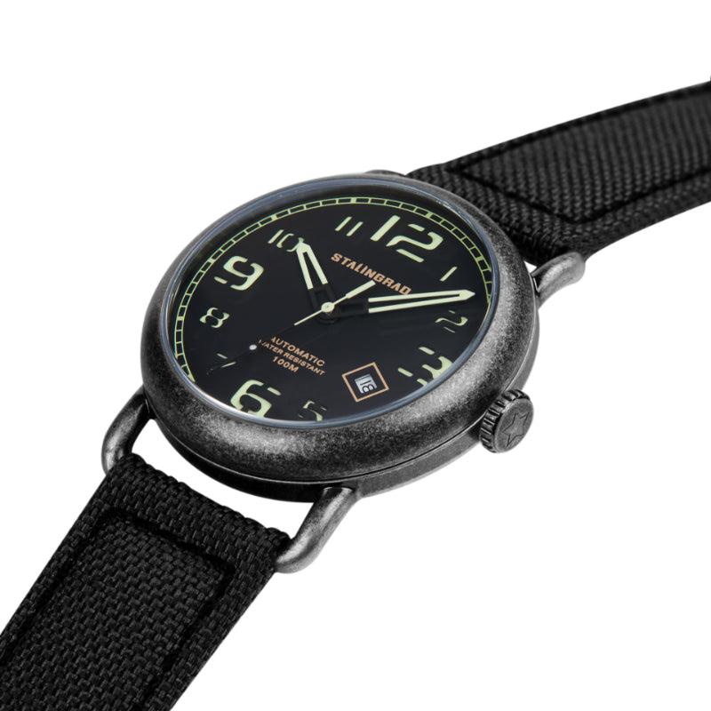 Stalingrad Rodim Watch with a sandwich dial. Black and green dial, black case and a black cordura strap, diagonal view of watch on white background.