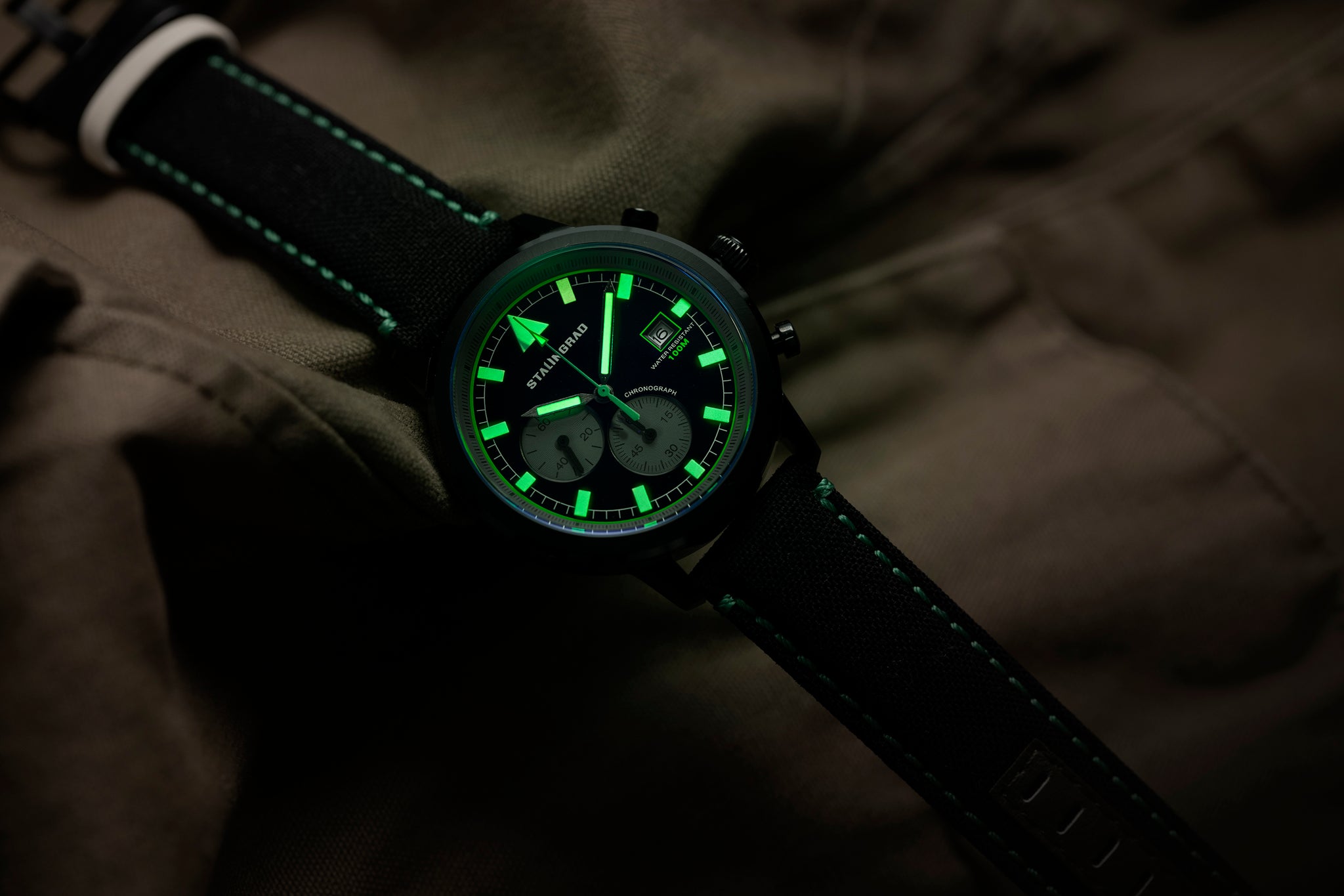 Stalingrad trooper chronograph watch with black case, black dial and black Cordura straps with bright green Lume hands and hour markers  diagonal view on a dark background 