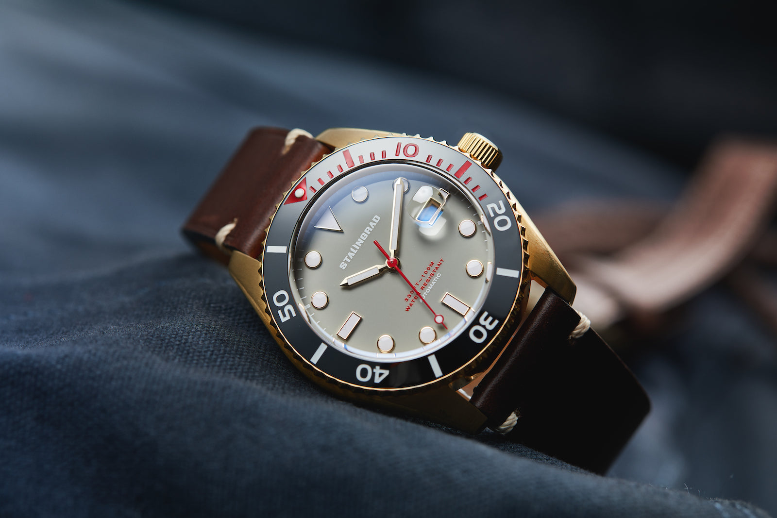 Stalingrad Volga defender automatic watch with a gold case and grey colour dial with red second hand in a brown leather strap, front view or watch on a dark background